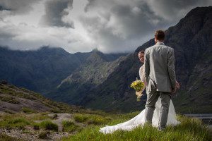 Bride peeks round groom at Loch Coruisk Skye with cuillin in background