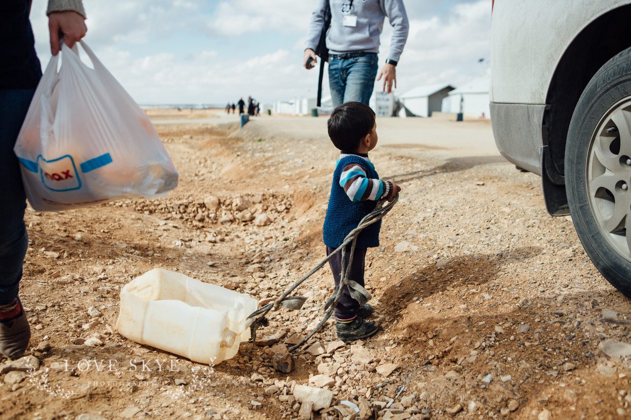 Toddler child Syrian refugee at Azraq camp Jordan with improvised toy 