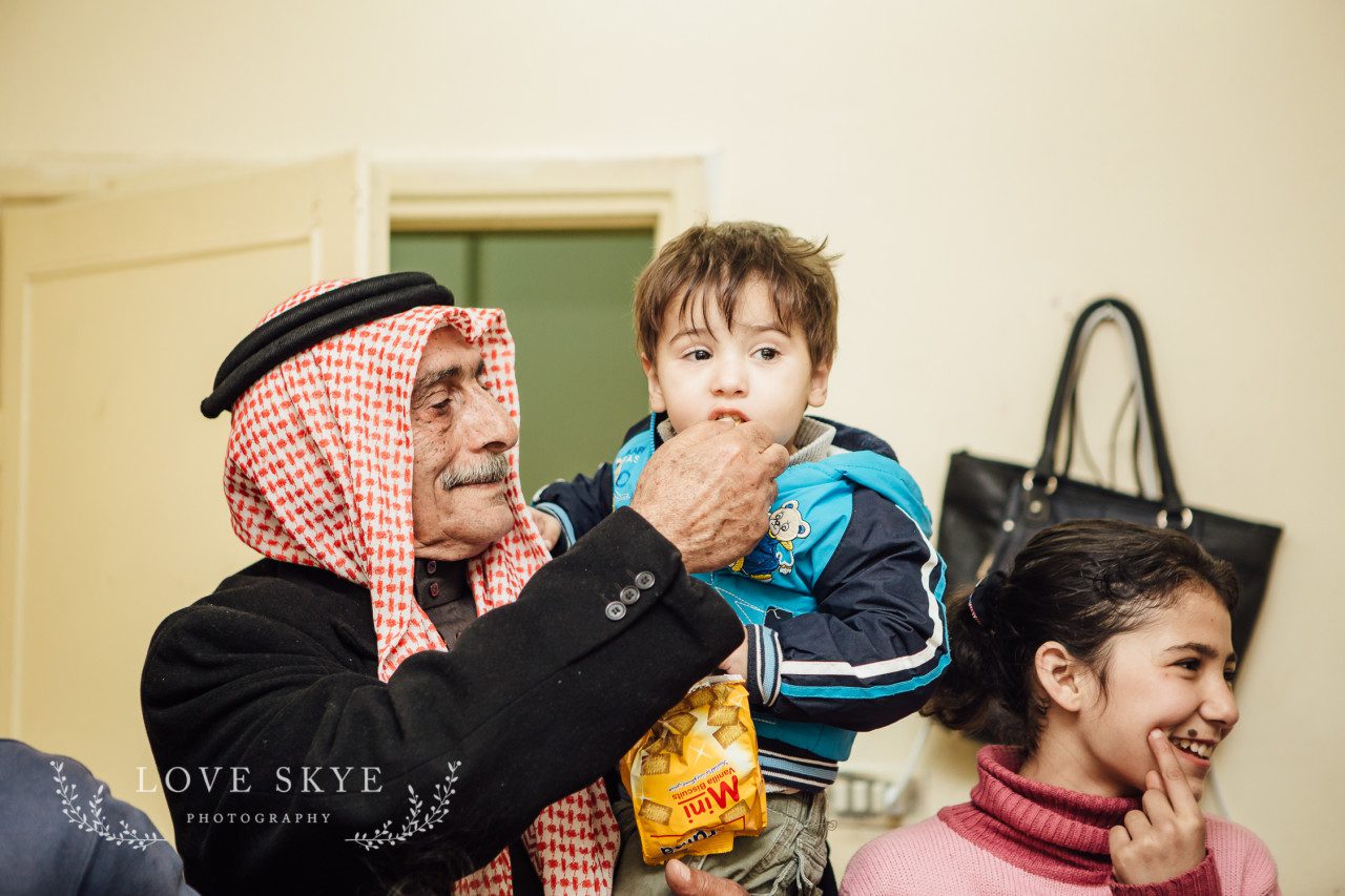 Syrian refugee grandfather holds grandchild Jordan