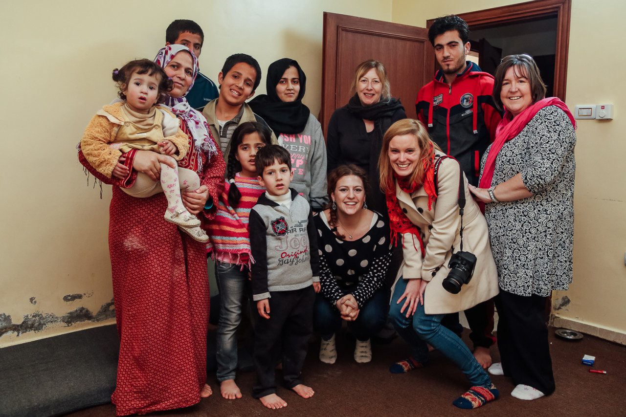 Syrian refugee family group in basement apartment northern Jordan pose with journalists