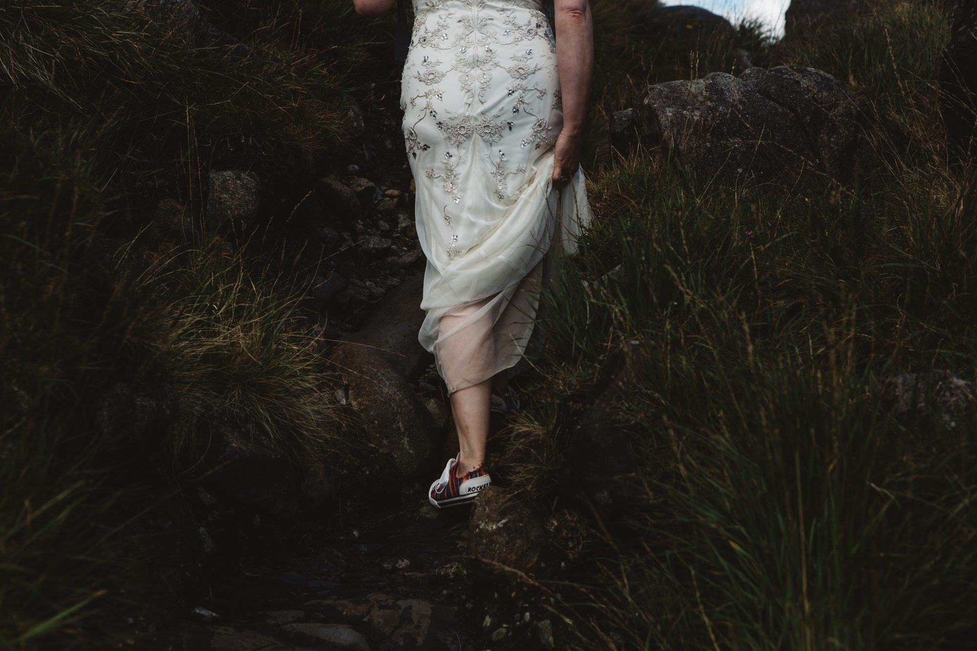 Bride and groom walk to ceremony among mountains loch coruisk