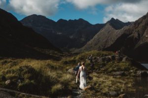 Bride and groom walk to ceremony among mountains loch coruisk