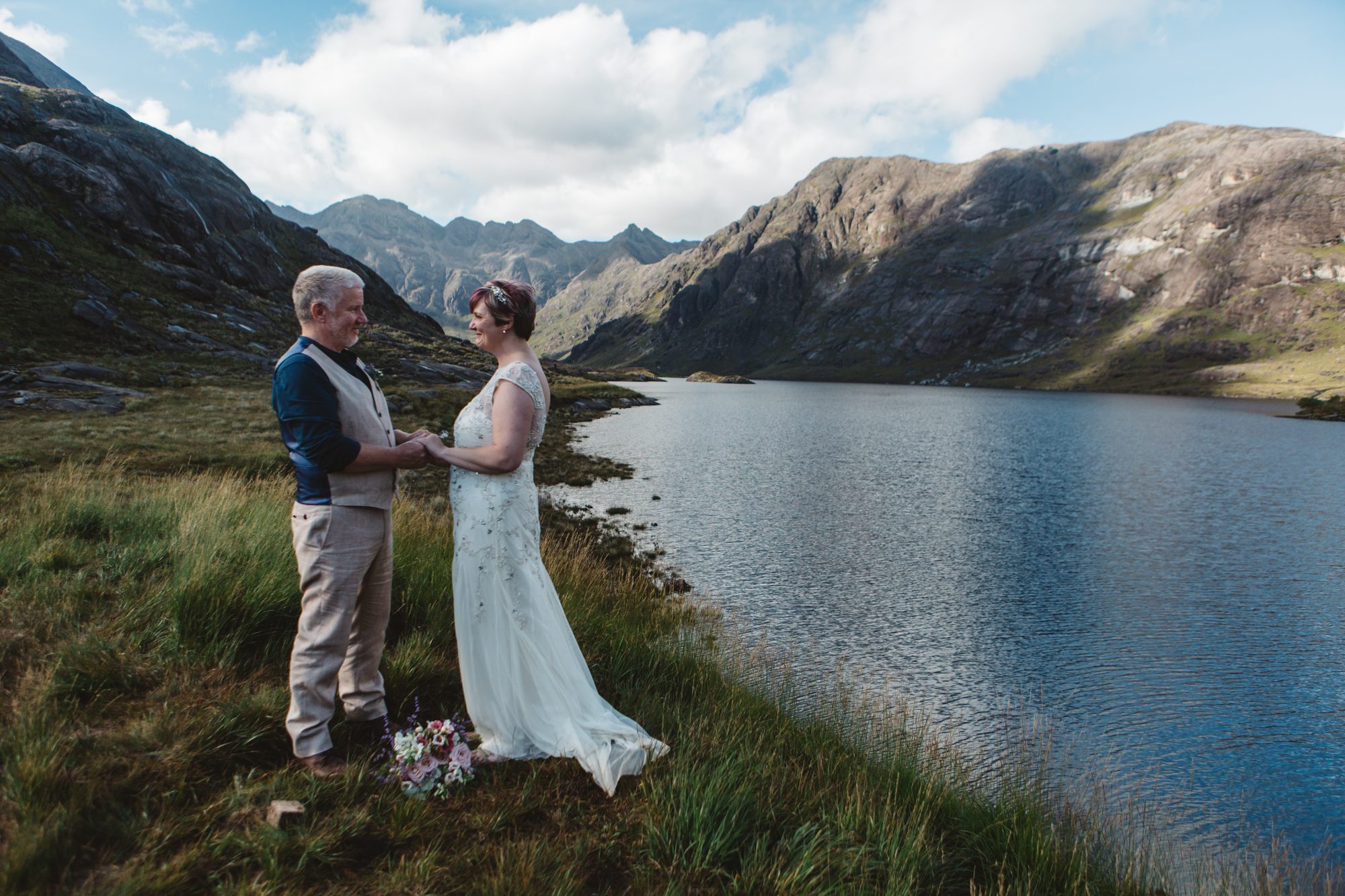 Bride and groom embrace during wedding ceremony loch coruisk