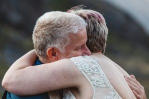 Bride and groom embrace during wedding ceremony loch coruisk