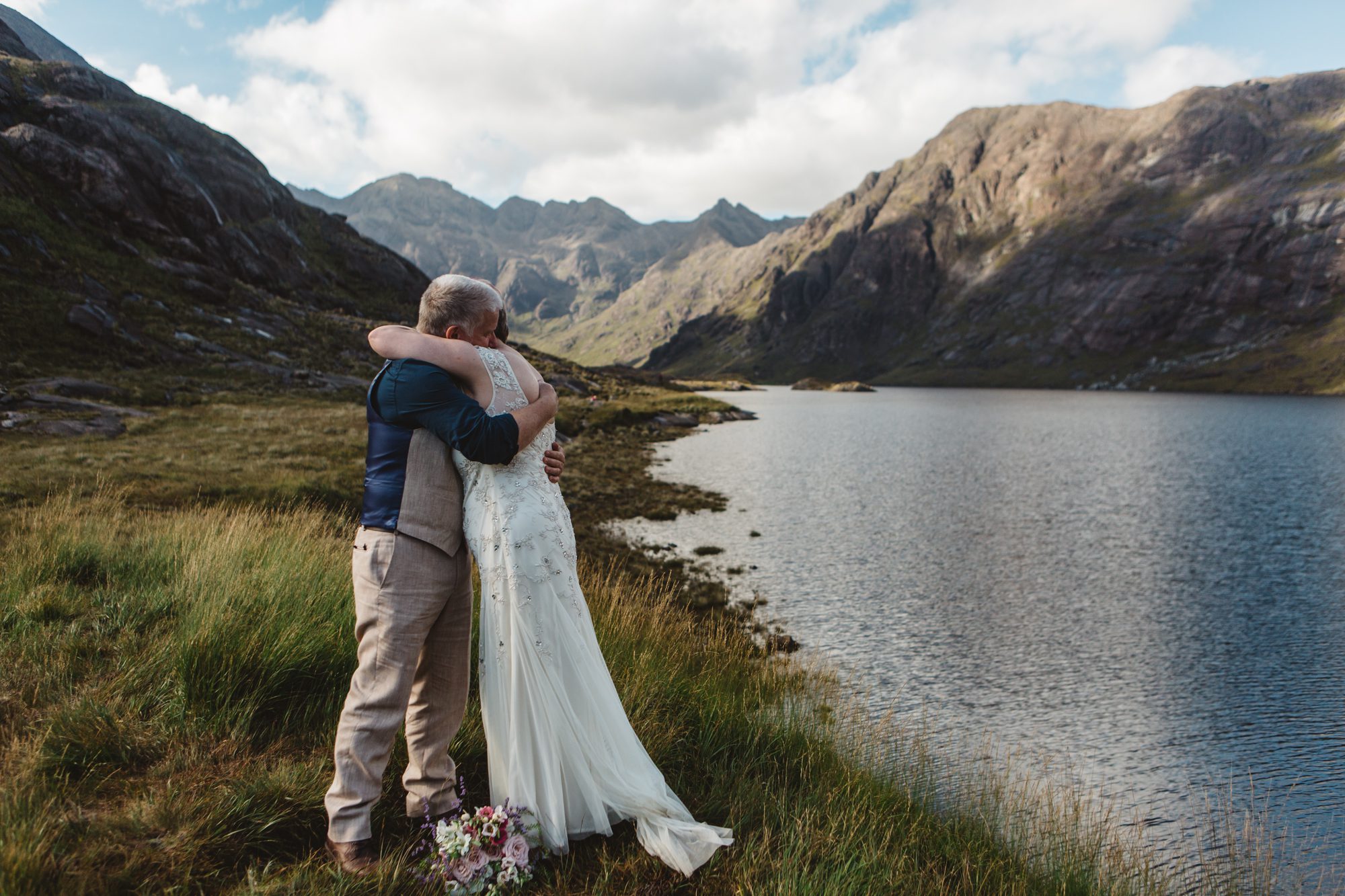 Bride and groom embrace during wedding ceremony loch coruisk