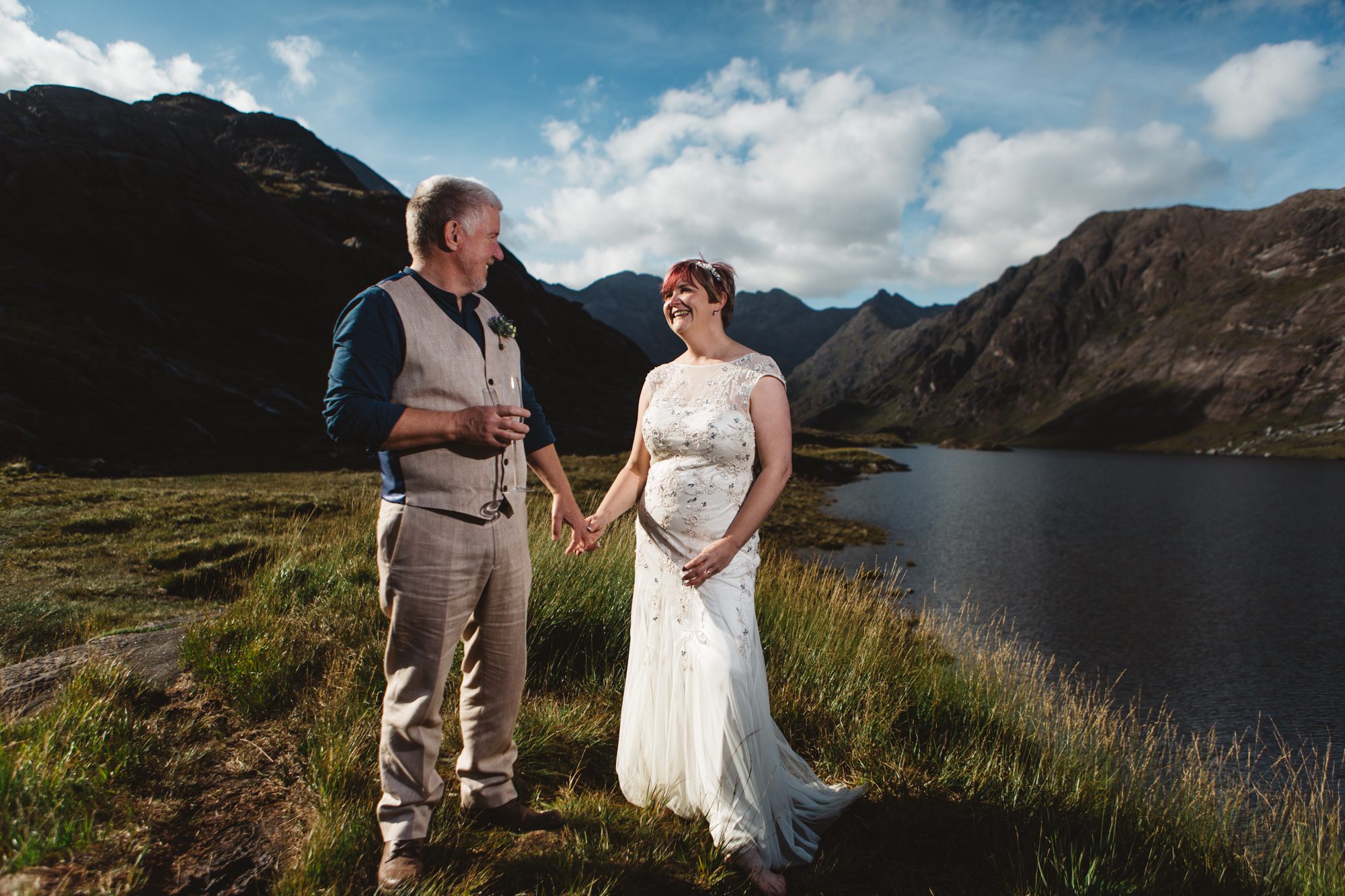 Bride and groom laughing and holding hands at Loch Coruisk