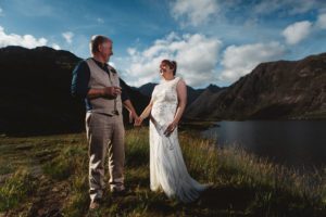 Bride and groom laughing and holding hands at Loch Coruisk
