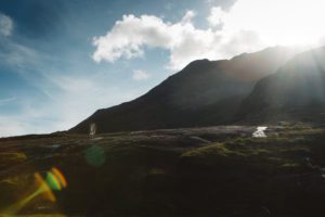 Tiny bride and groom on rock slabs with sun flare at Loch Coruisk