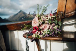wedding bouquet of pink and wild flowers on wooden seating of Misty Isle boat
