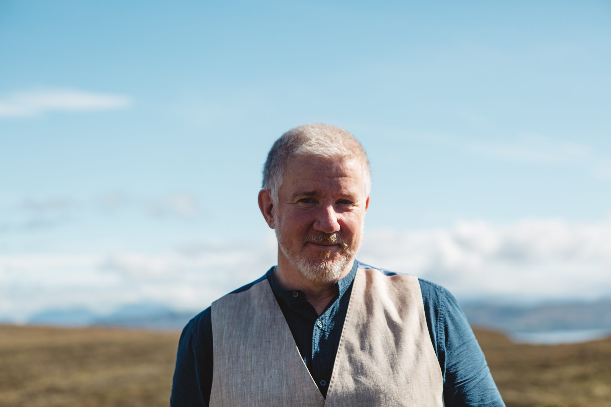 slightly anxious groom with short white beard and blue sky and hills in background