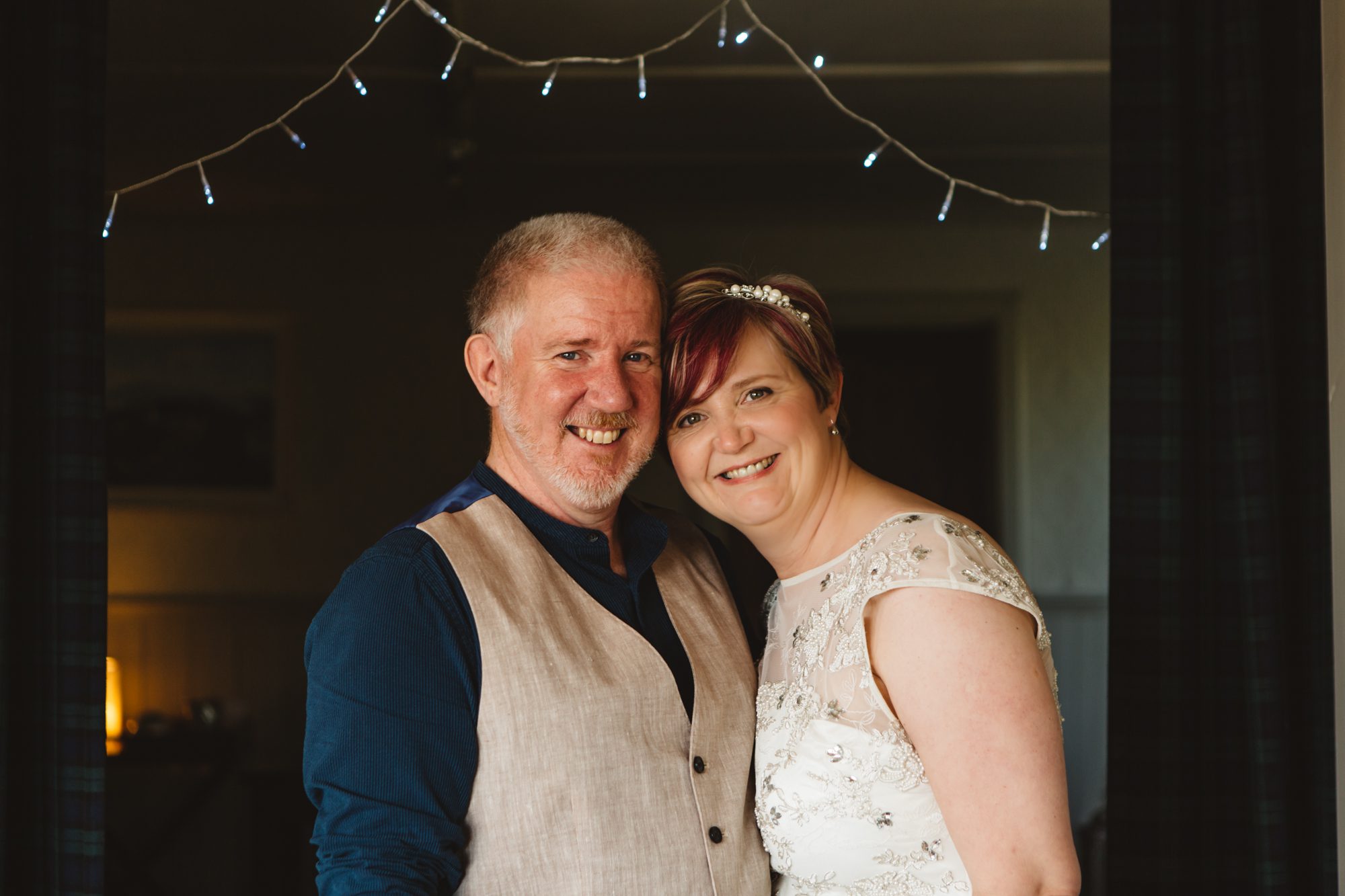 smiling bride and groom with fairy lights