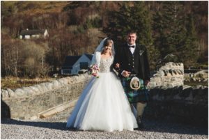 Father walks daughter bride across bridge at Eilean Donan Castle