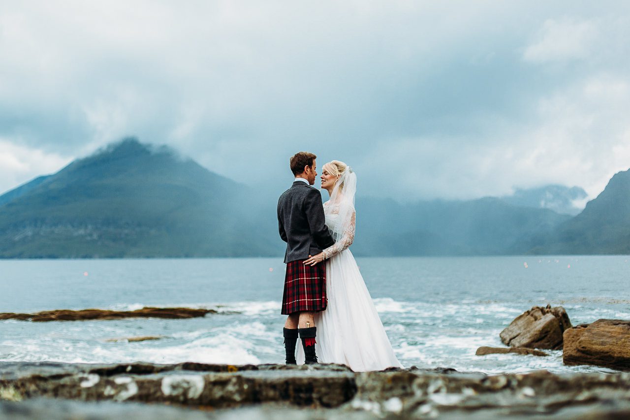 Bride and groom on rock slabs at Elgol view of Cuillins Isle of Skye