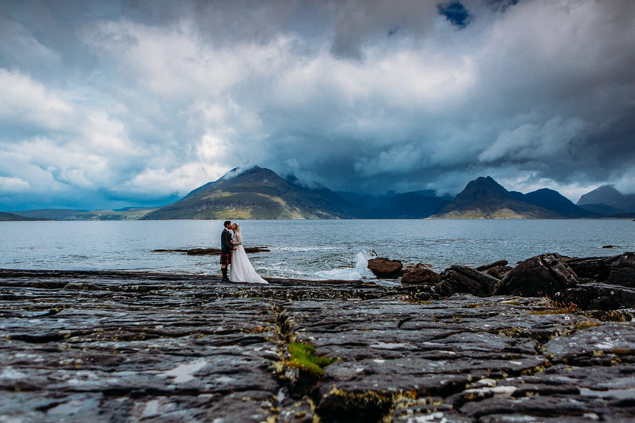 Bride and groom on rock slabs at Elgol view of Cuillins Isle of Skye