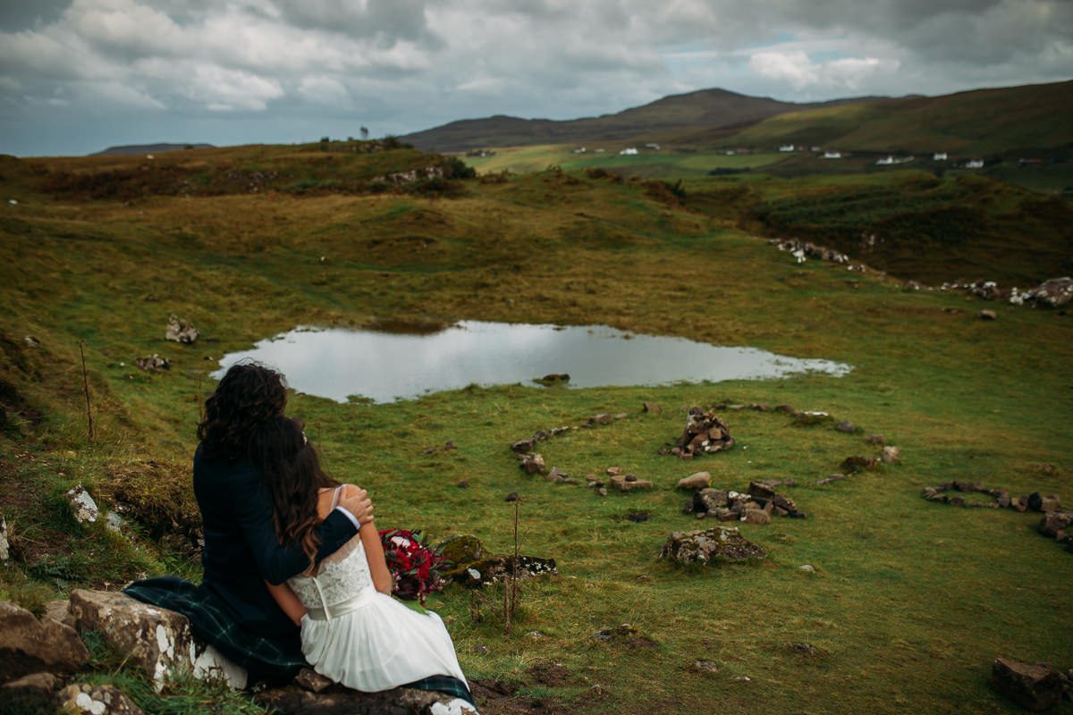 Bride and groom seated by waterfall Isle of Skye