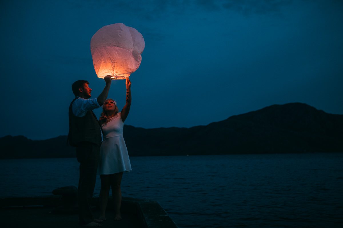 Sky lanterns at sunset Knoydart Scotland held by bride and groom