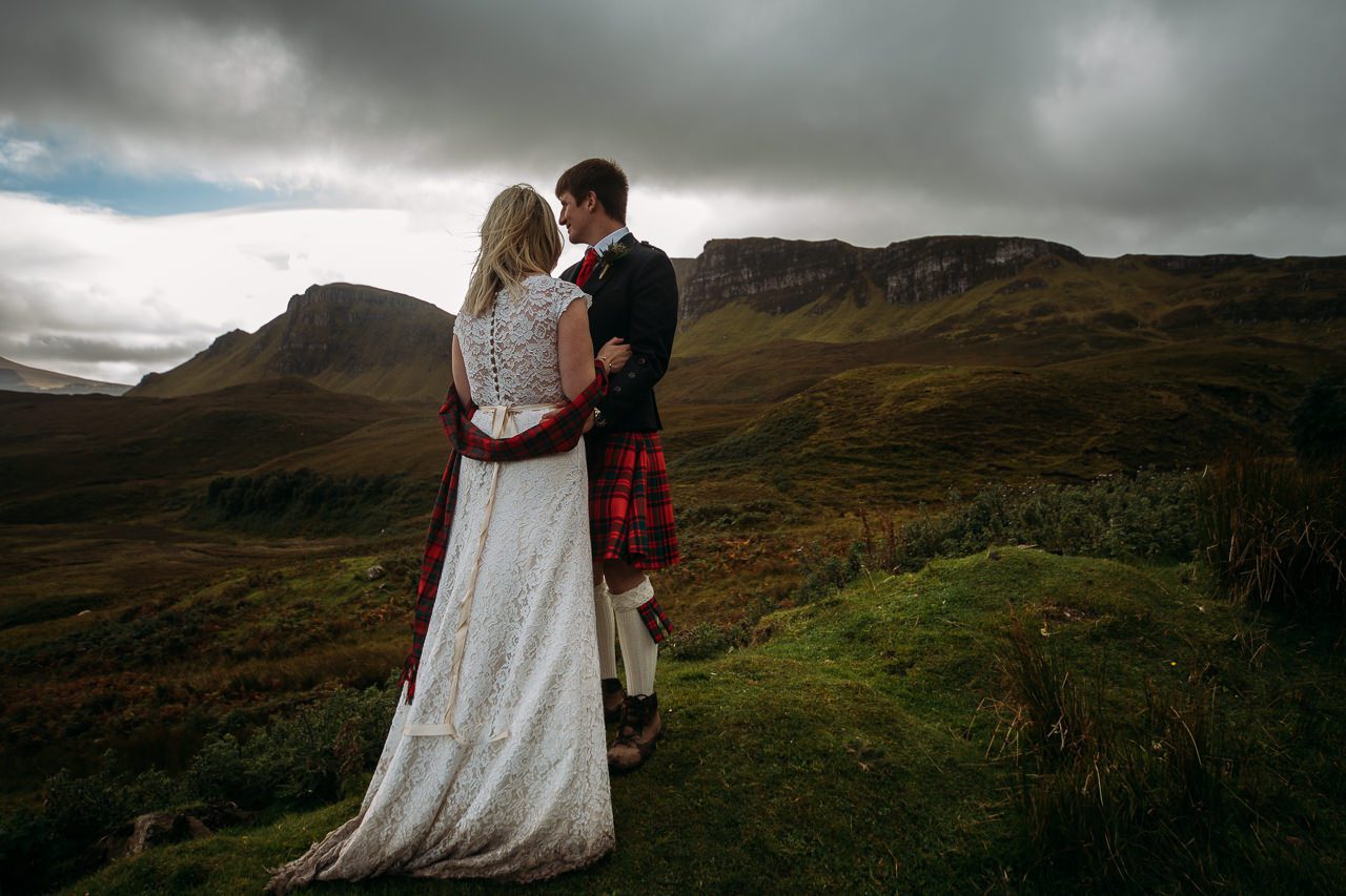 Kilted groom and bride facing to sea from Quiraing Isle of Skye wedding