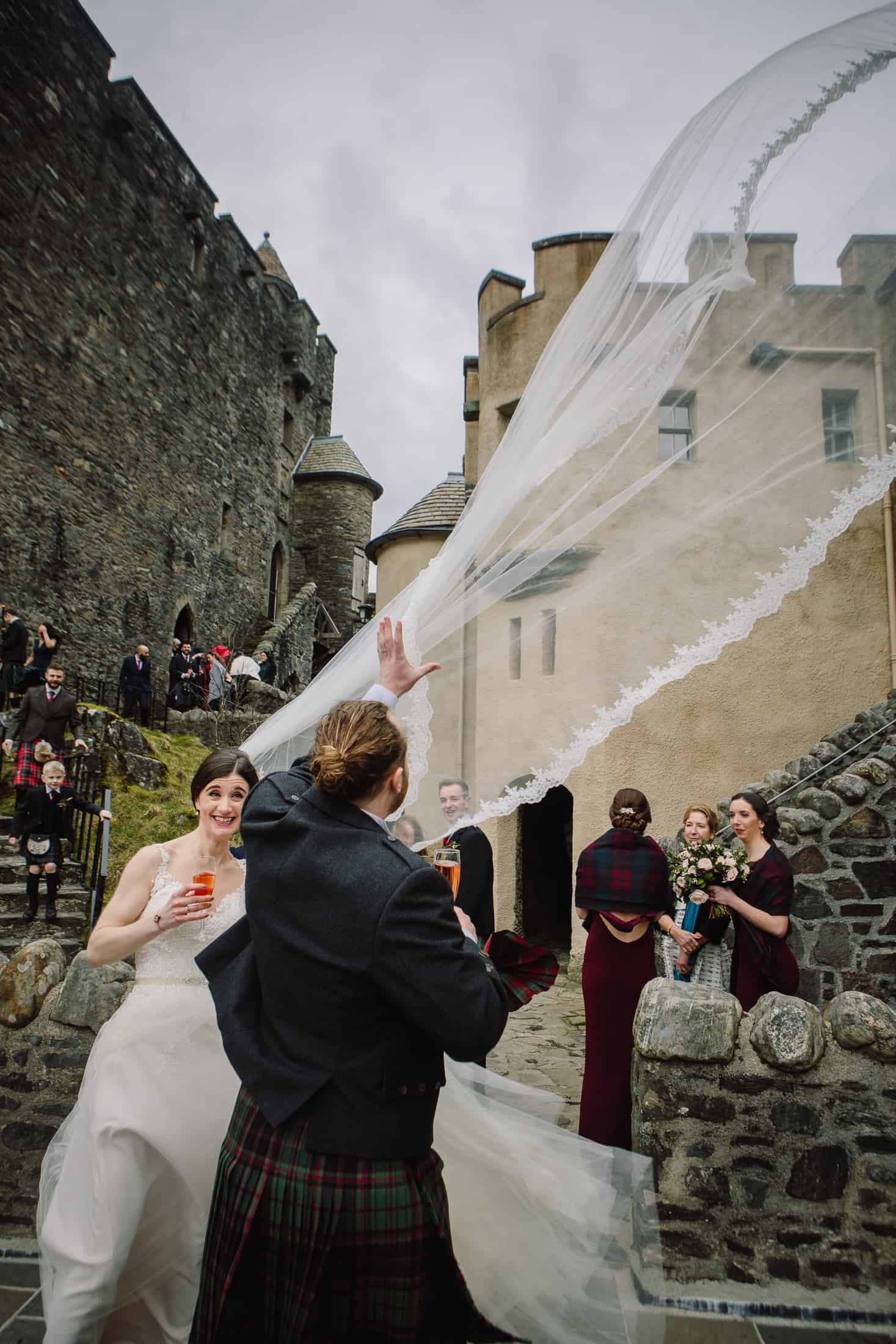 Bride's veil caught in breeze courtyard Eilean Donan castle wedding