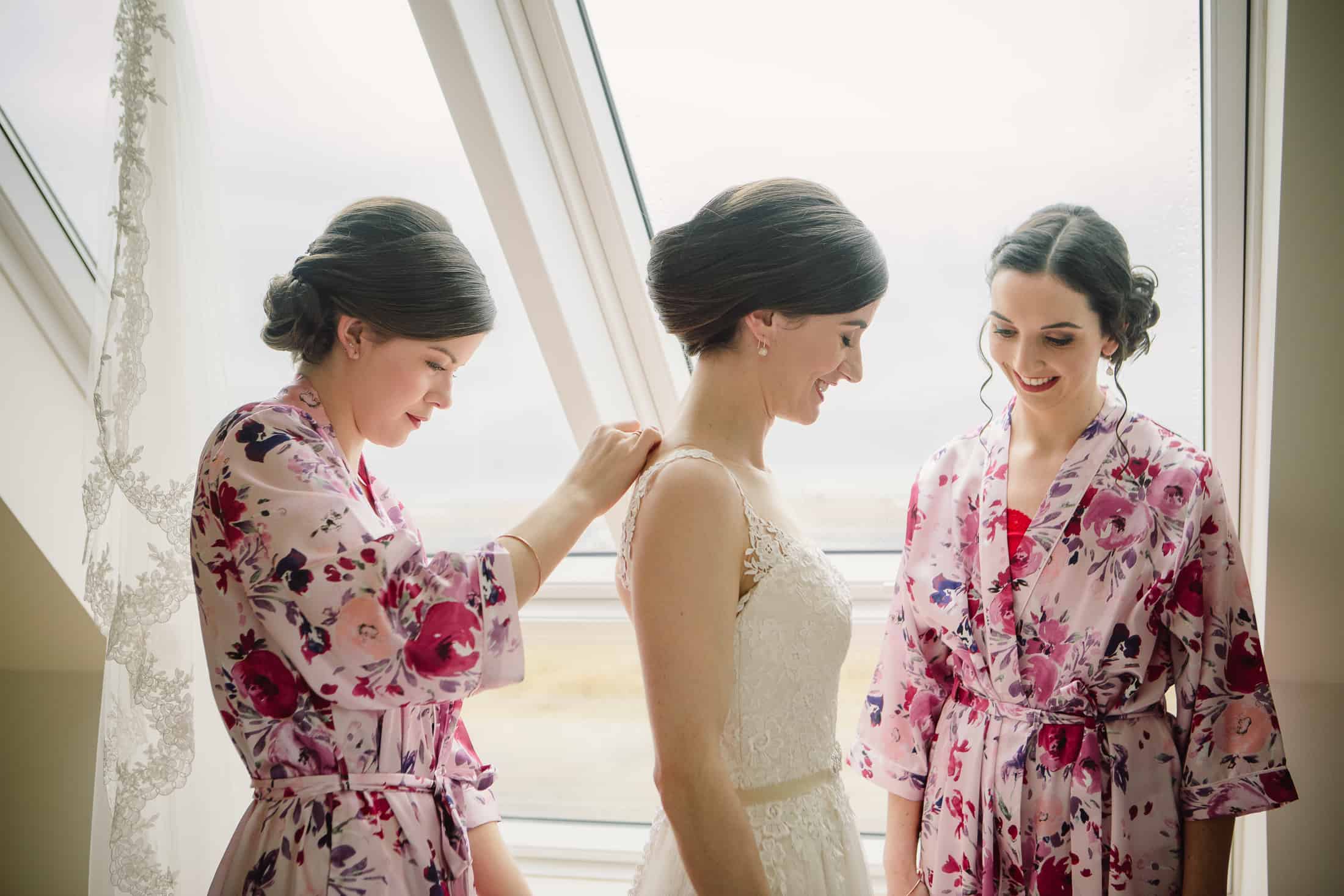 Bridesmaids helping bride with wedding dress Isle of Skye