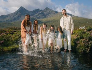 Family vacation photograph splashing in a river with Cuillin mountain Isle of Skye