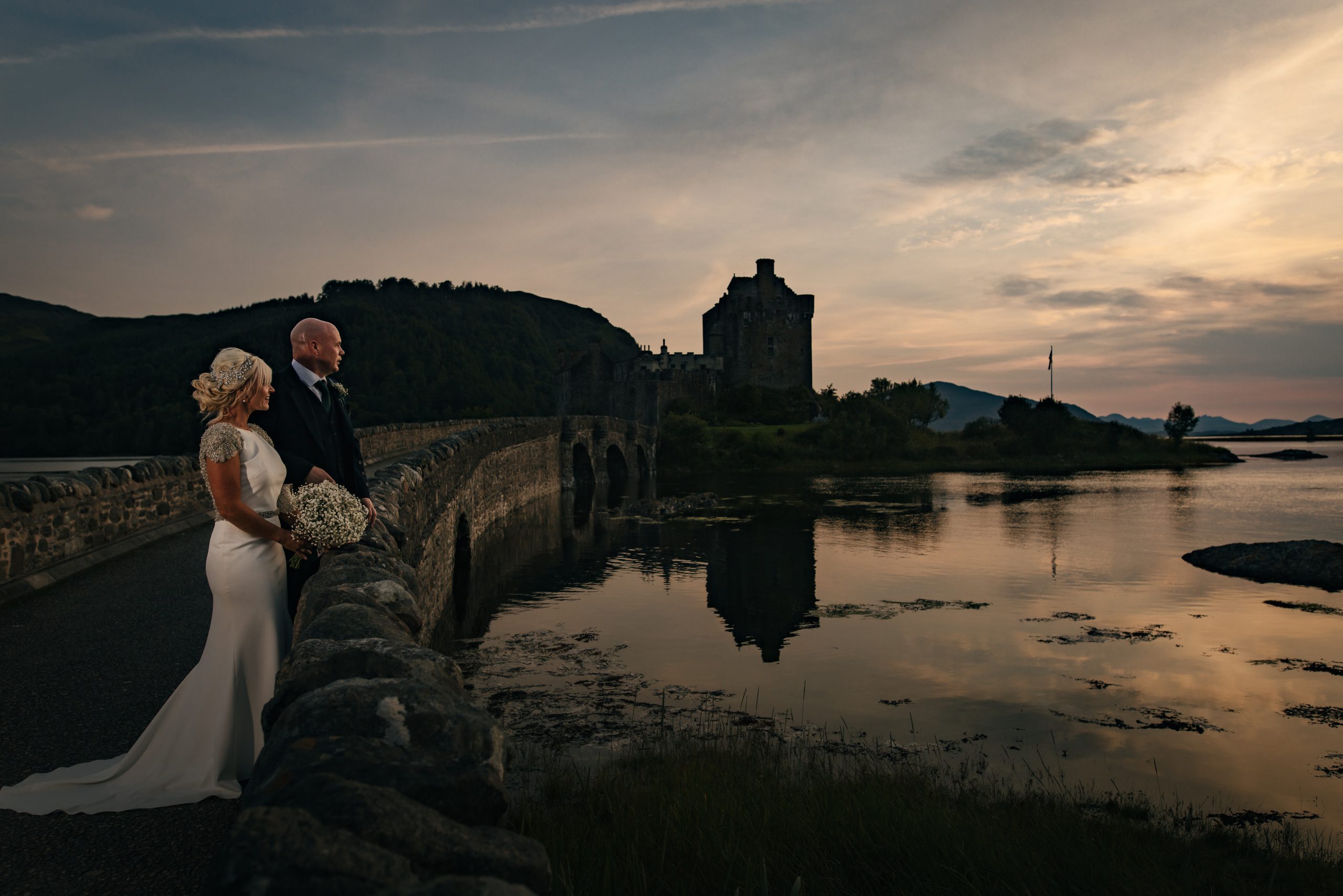 Eilean donan Castle wedding at sunset. Bridal couple on bridge to castle