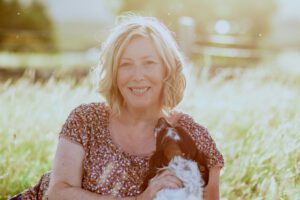 Rosie Woodhouse with her spaniell in sunshine in a grass field Isle of Skye